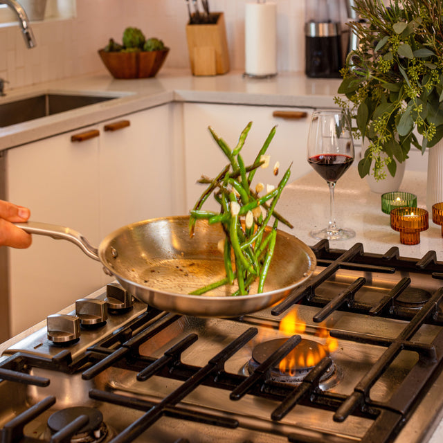 A stainless pan working over a tall open flame