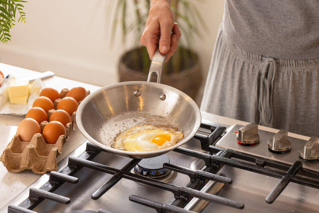 An egg cooking in a stainless steel fry pan