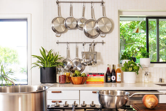 Stainless steel pans hanging clean and ready in a bright home kitchen