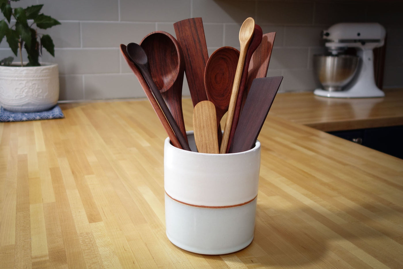 Set of wooden spoons in a white container on a kitchen counter