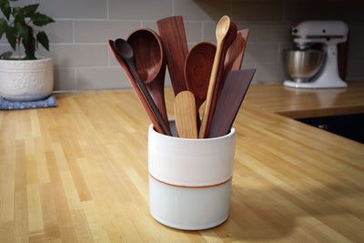 Set of wooden spoons in a white container on a kitchen counter